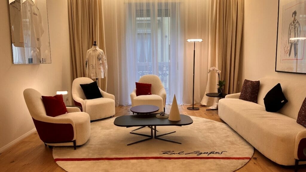תצוגת רהיטי סלון - ספה, שלוש כורסאות, שני שולחן סלון ושטיח עגול עם הכיתוב קארל לגרפלד